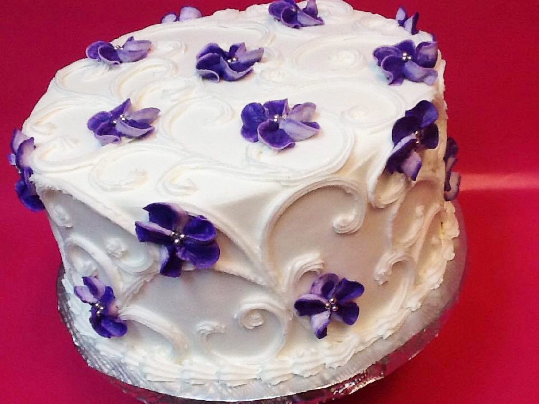 White cake with piped purple flowers