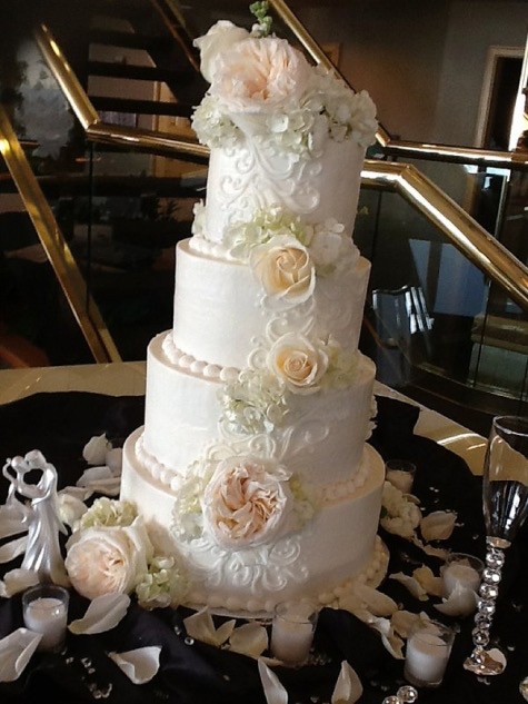 Tall five-tier white wedding cake trimmed with blush roses