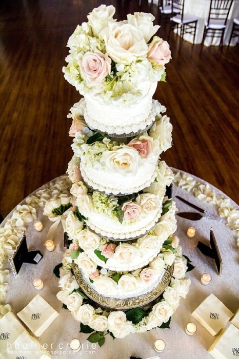 White wedding cake with cascading blush roses under string lights