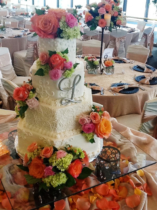White wedding cake with a cascade of orange, coral, and purple flowers