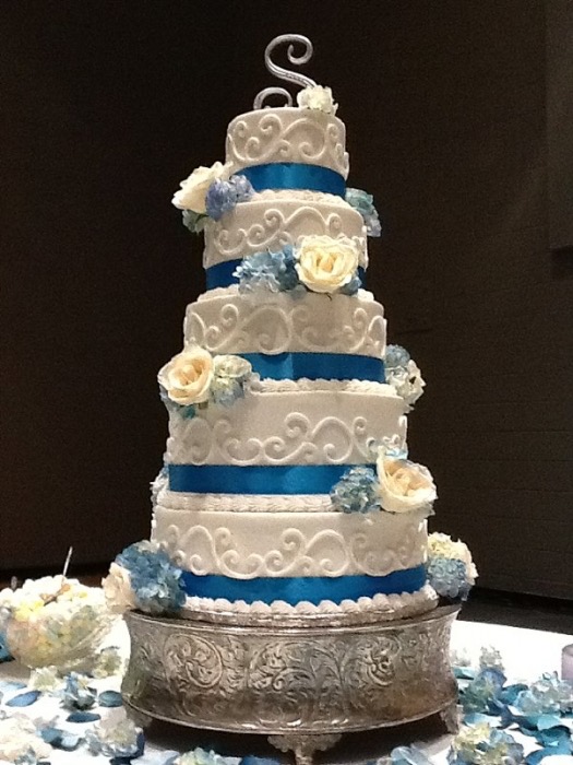 White wedding cake with a navy ribbon and fresh roses