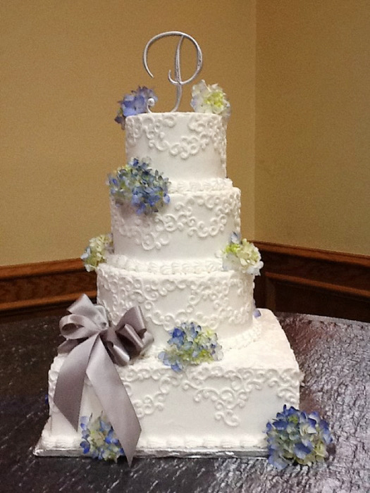 White square wedding cake with lavender and blush flowers and a gray bow