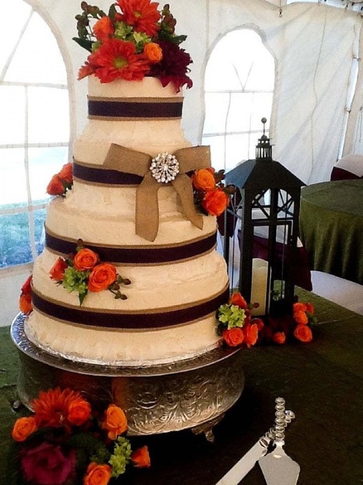 White and gold wedding cake with red roses and a bow